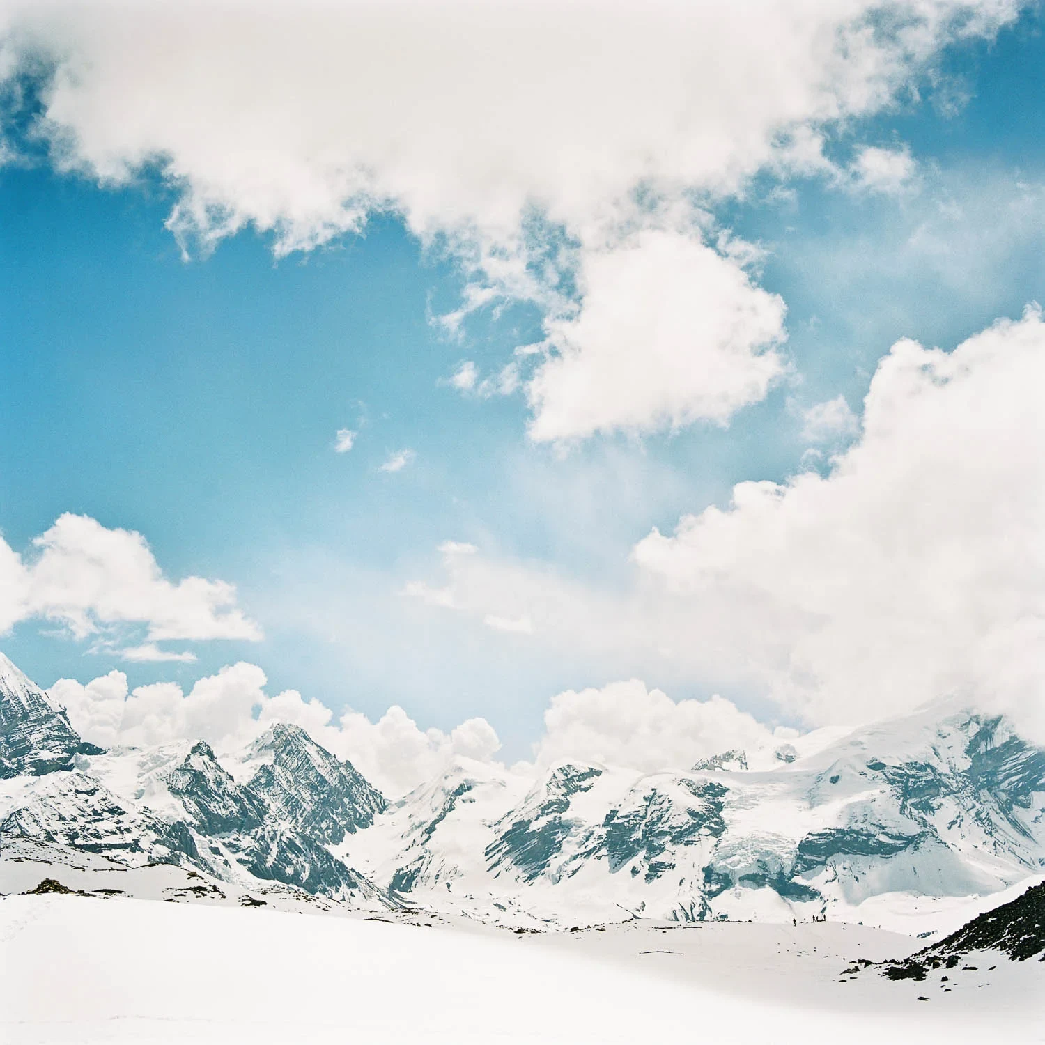 Bright clouds above a wide panorama of snowy Himalayan peaks.