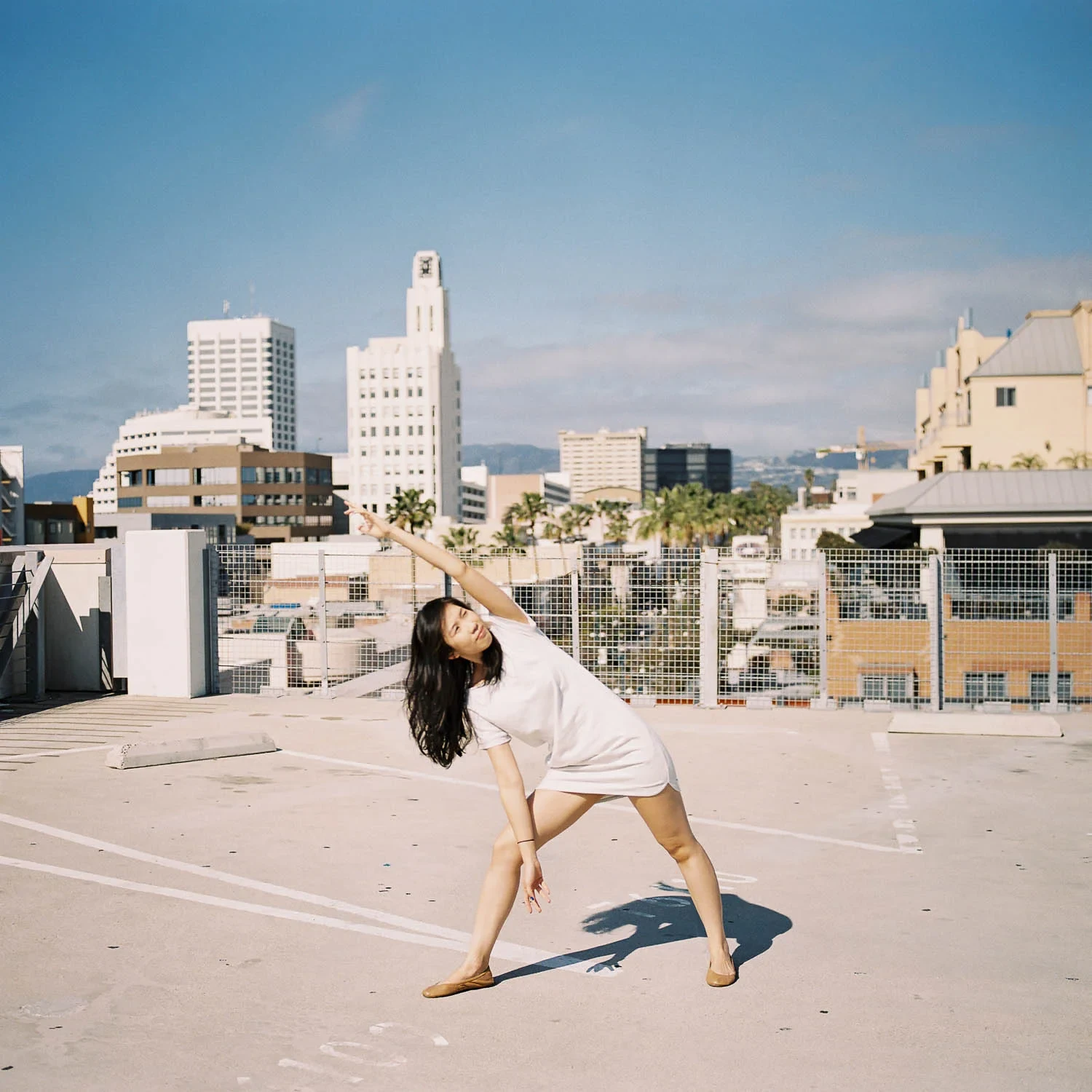 Woman leaning sideways playfully on a sunny rooftop.