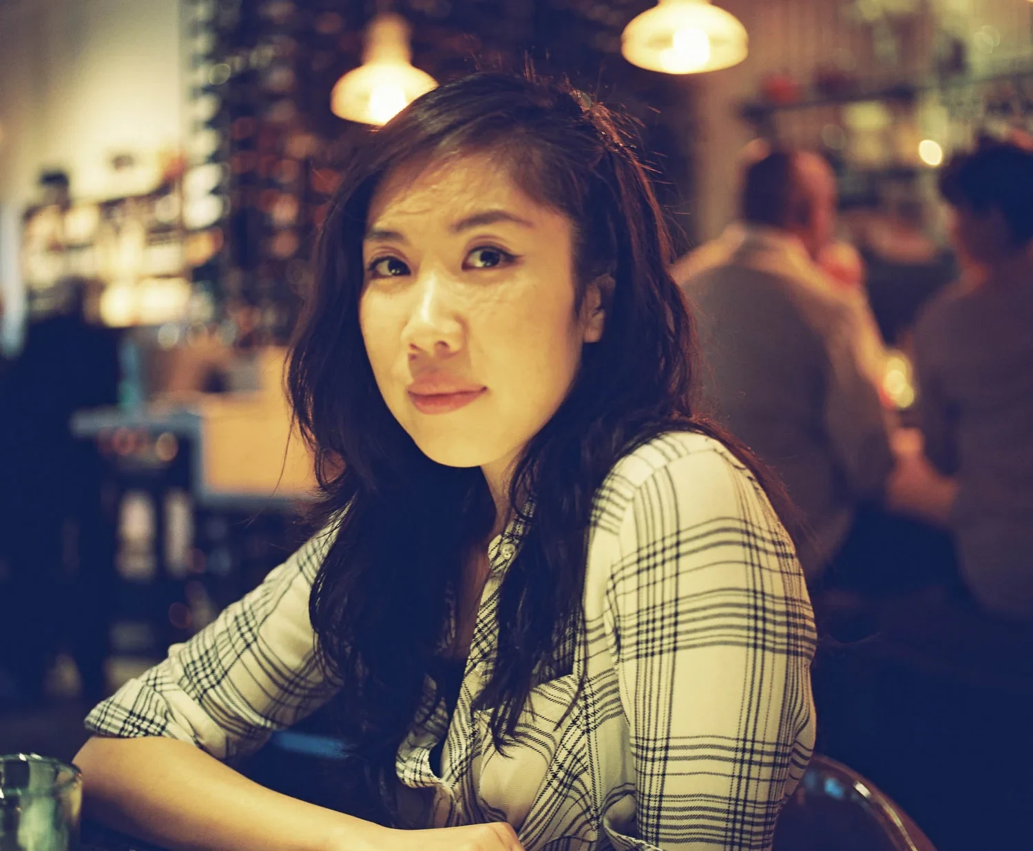 Warmly lit portrait of a woman seated inside a café.