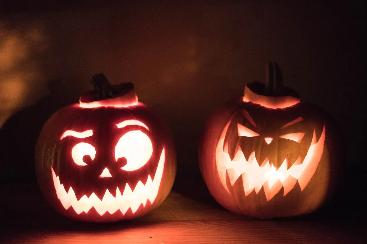 Two illuminated Halloween pumpkins with carved grinning faces.