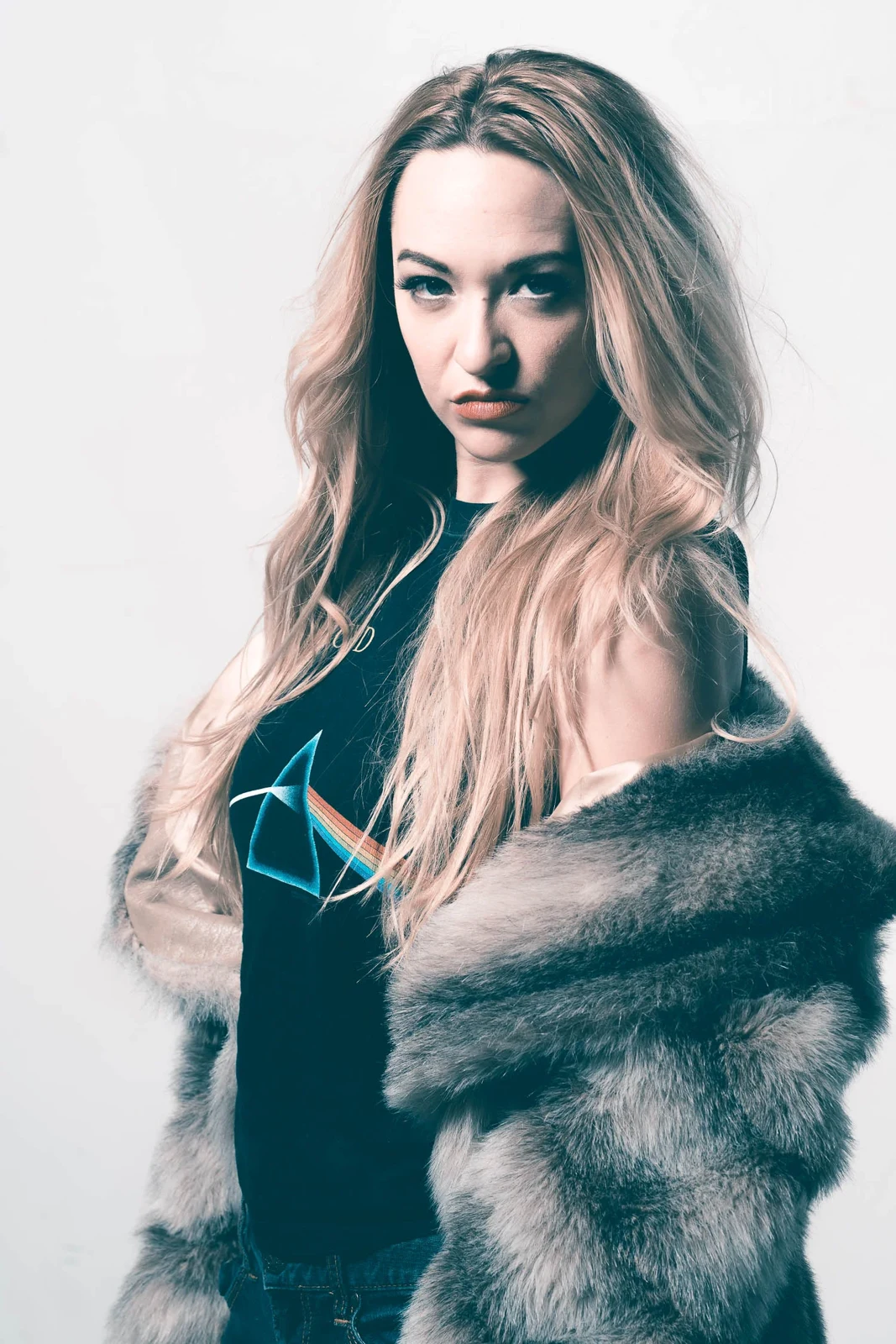 Portrait of a woman with long pale hair wearing a dark fur-textured jacket.