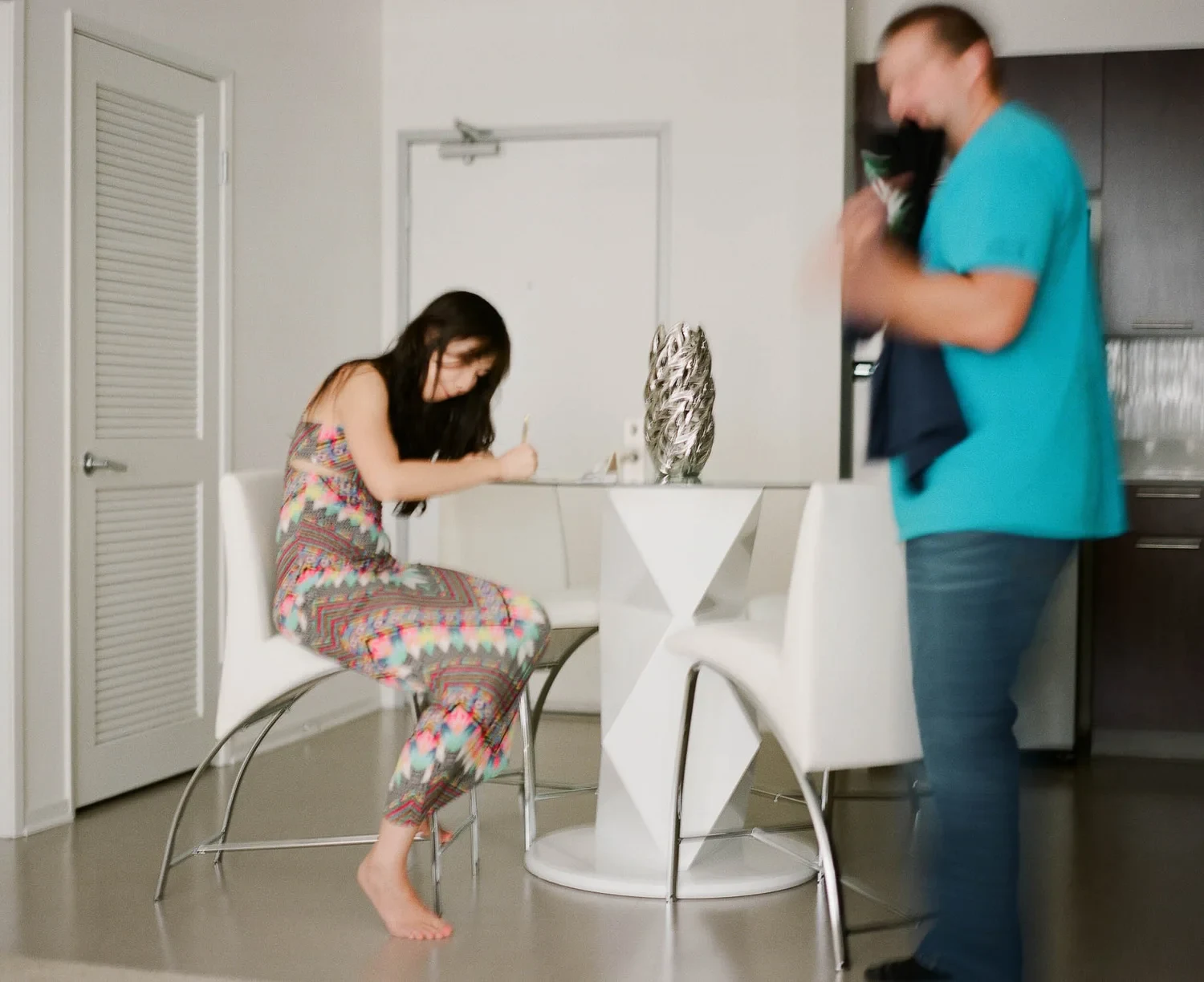 Woman sitting at a small table while a person stands nearby.