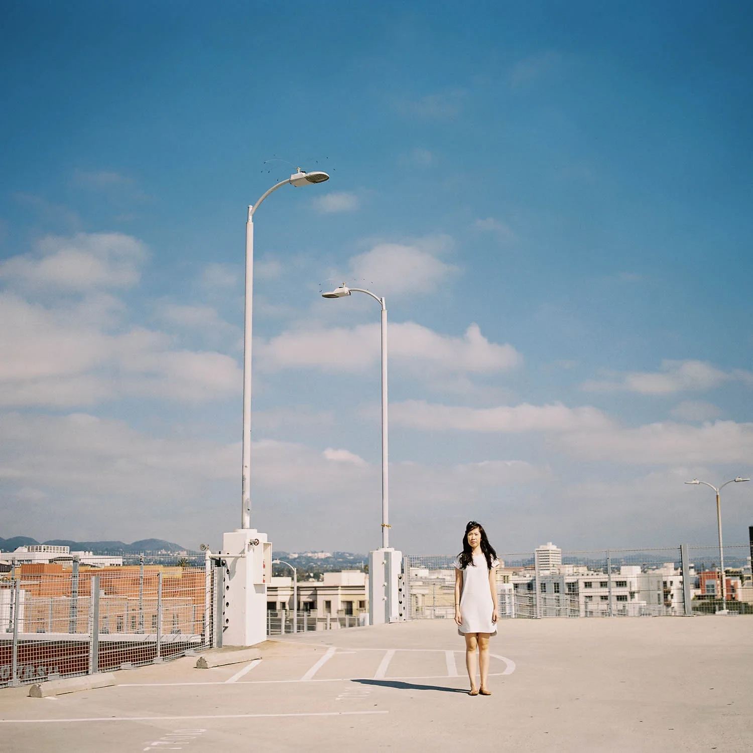 Woman beneath a tall lamp on an open city rooftop.