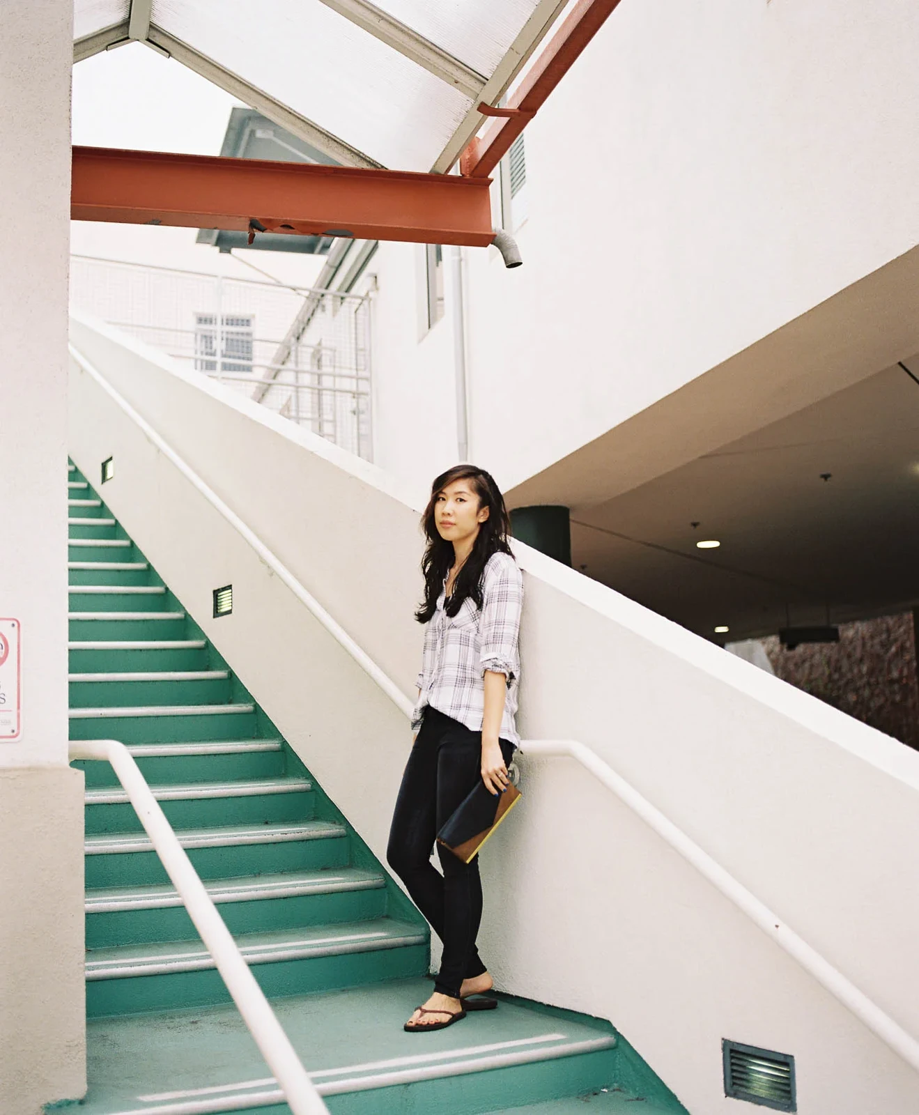 Woman standing beside a broad staircase inside a bright building.