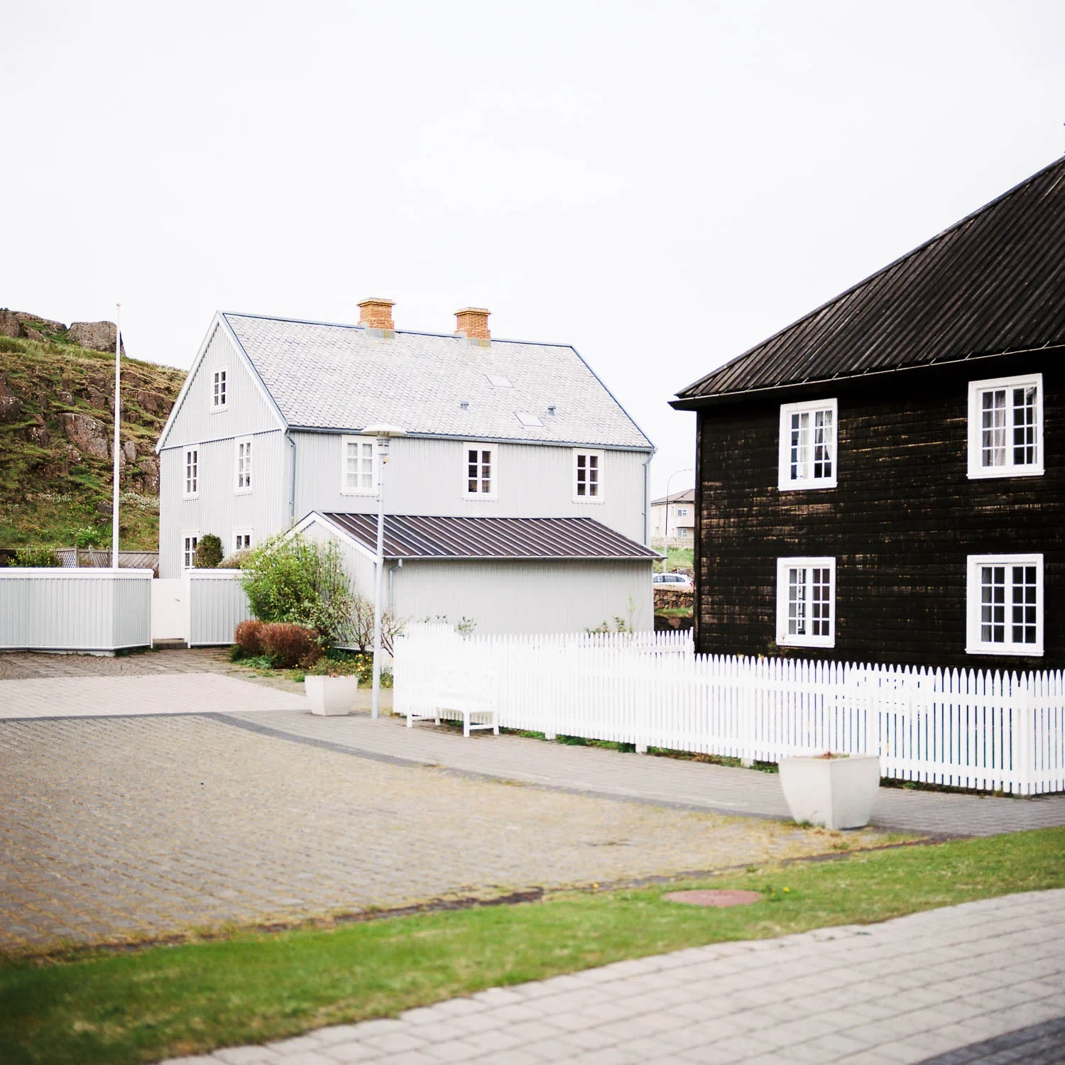 White and dark timber houses beside a quiet street.