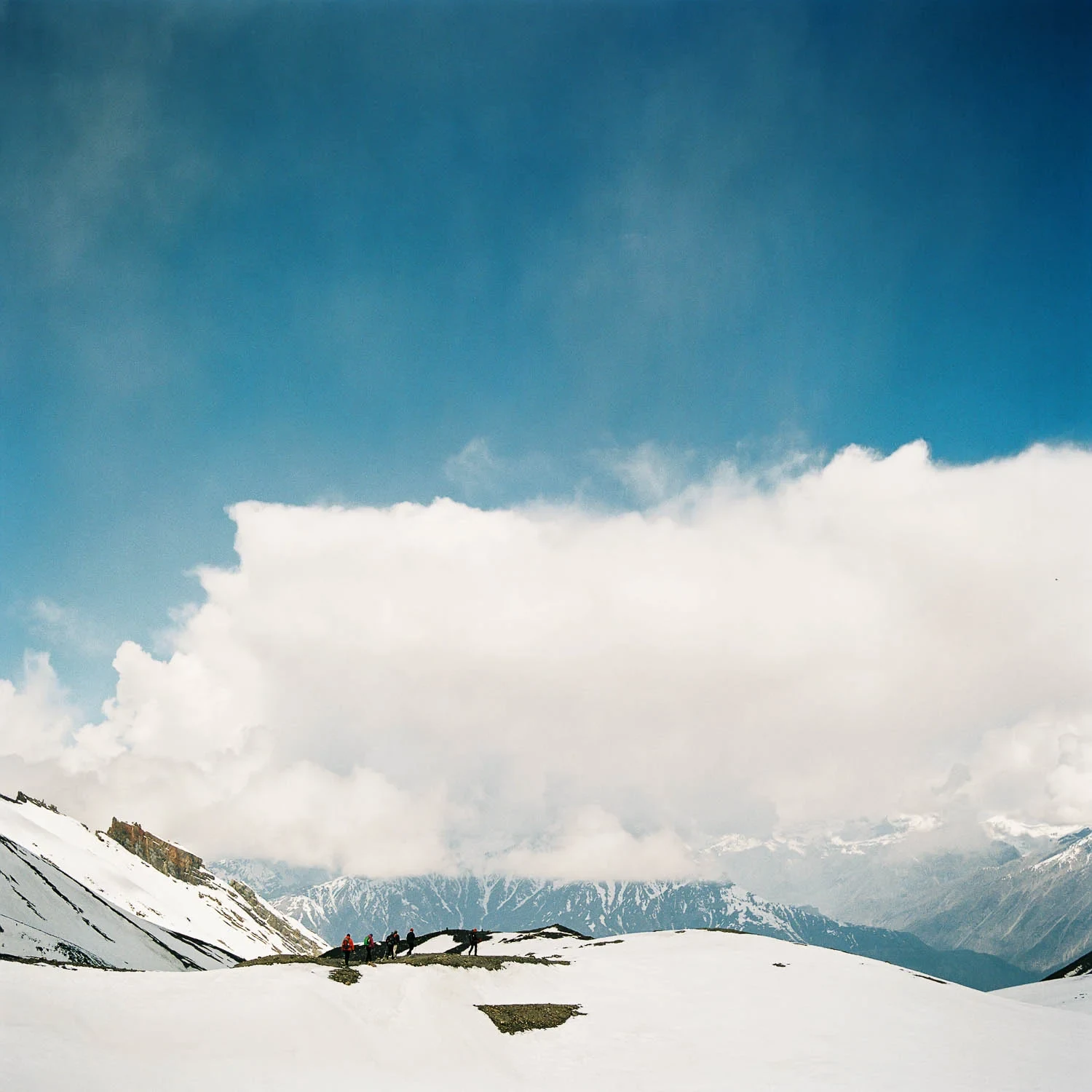 Snow-covered mountains beneath a large white cloud in Nepal.
