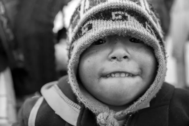 Black-and-white close portrait of a child wearing a patterned knit hat.
