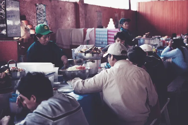 People gathered around tables in a busy indoor dining space.