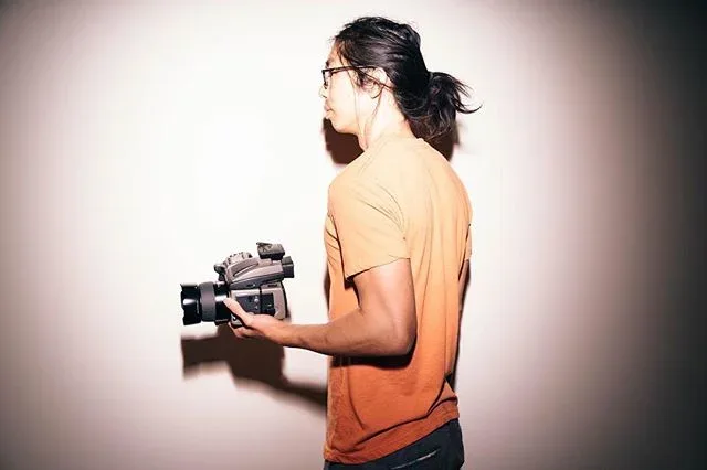 Side portrait of a photographer holding a camera in warm light.