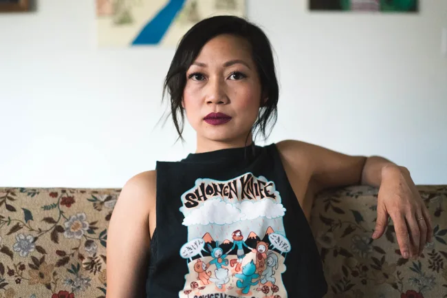Woman in a black graphic top seated on a patterned sofa.