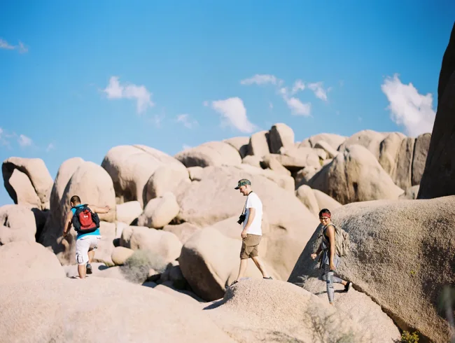 People exploring rounded granite boulders in Joshua Tree.