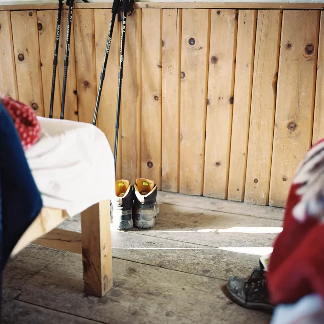 Hiking boots resting beside a bed in a wood-paneled room.