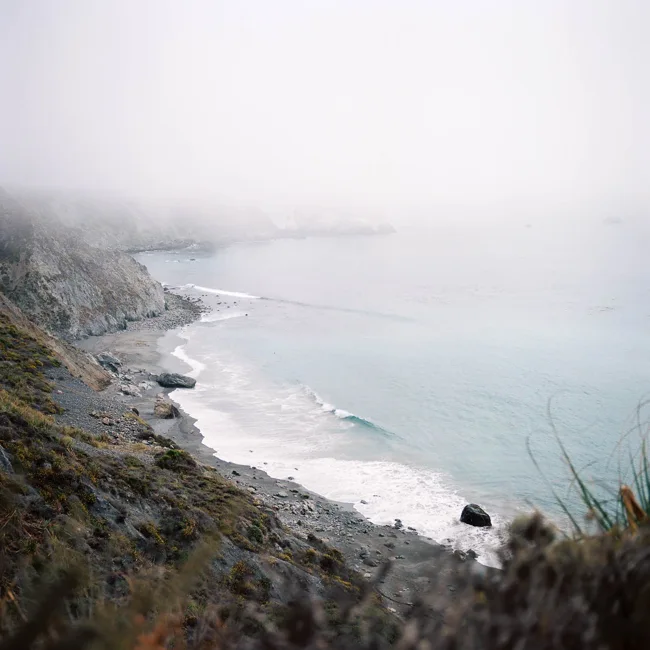 Rocky Pacific coastline fading into coastal fog.