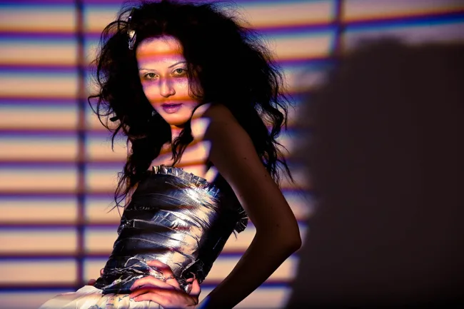 Bands of colored light fall across a model in a metallic top.