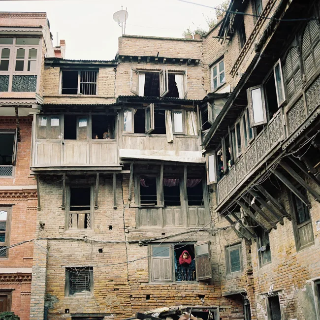 Aged multistory buildings with wooden windows in a Nepalese courtyard.