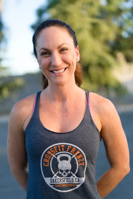 Smiling woman in an athletic tank top outdoors.