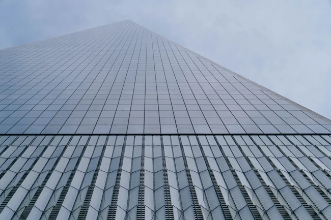 Glass skyscraper disappearing upward into fog.