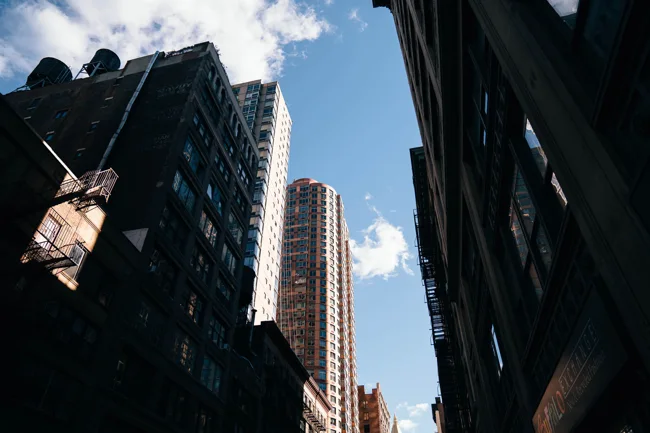 New York skyscrapers viewed upward from a narrow street.
