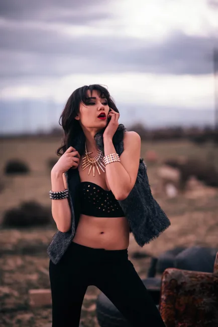 Model wearing sunglasses and a black crop top in an open field.