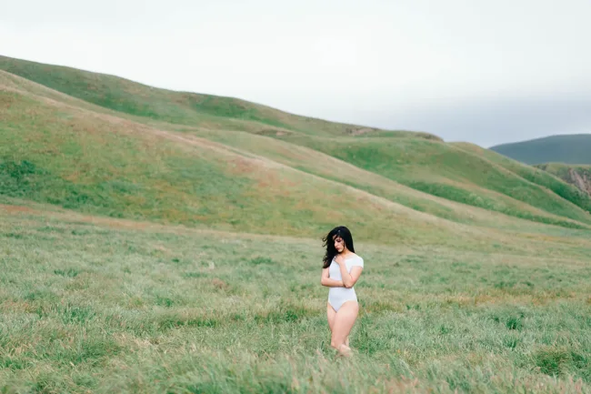 Distant model in white standing in a broad green valley.