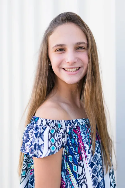 Smiling young woman in a blue floral off-shoulder top.