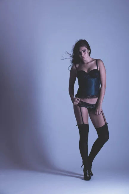 Full-length studio portrait of a model in black stockings and heels.