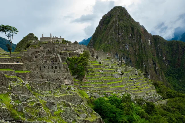 Stone terraces and ruins at Machu Picchu beneath a steep green peak.