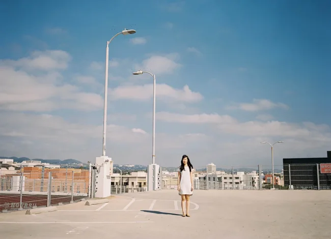 Model standing on an open rooftop beneath a blue sky.