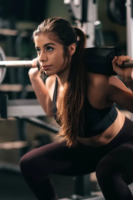 Woman exercising with a barbell in a gym.