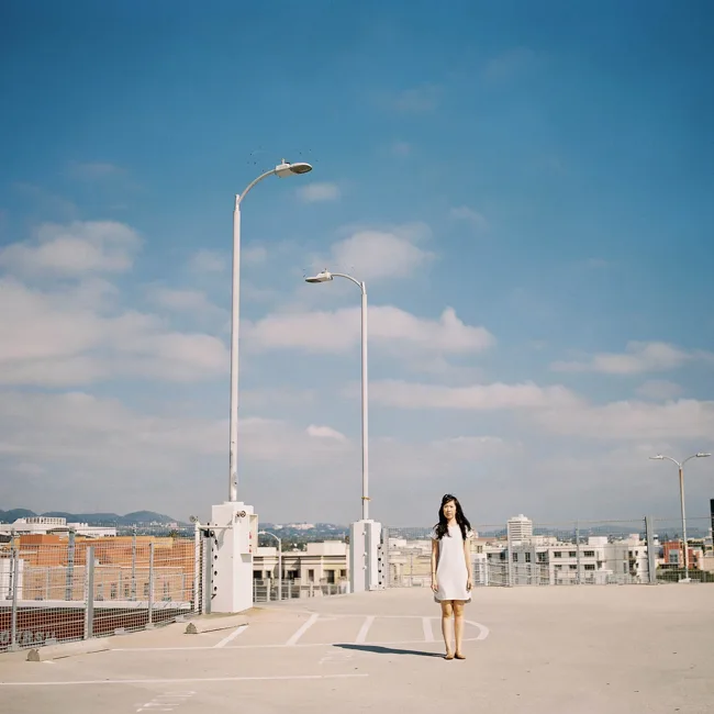 Woman beneath a tall lamp on an open city rooftop.