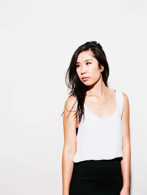 Model in a white tank top and black skirt against a white background.