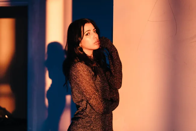 Model in a textured sweater lit by warm sunset light.