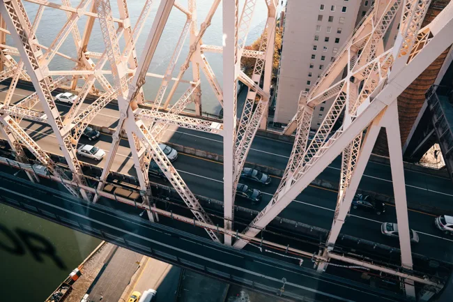 Intersecting steel beams of a large bridge viewed from below.