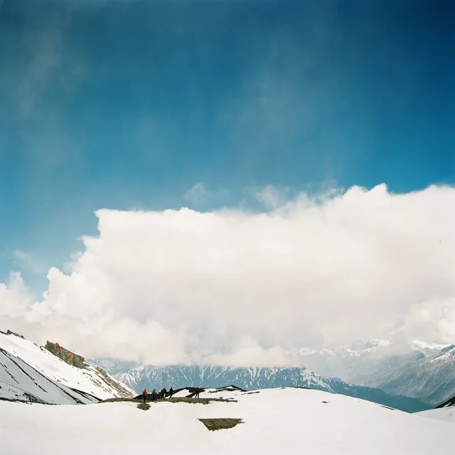 Snow-covered mountains beneath a large white cloud in Nepal.