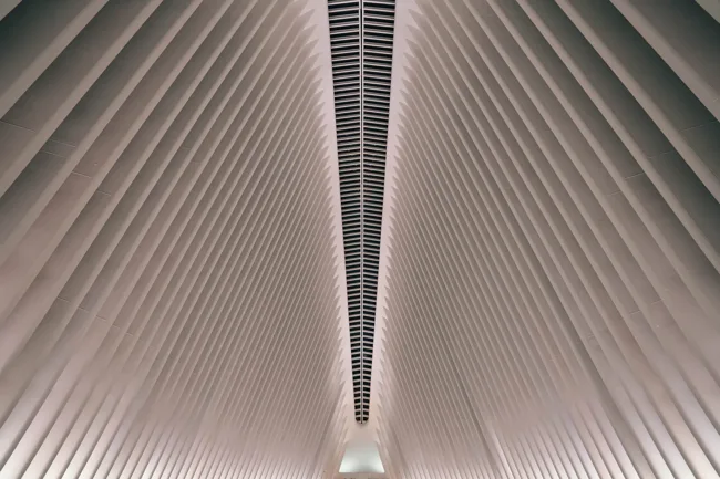White architectural ribs converging along a narrow ceiling opening.
