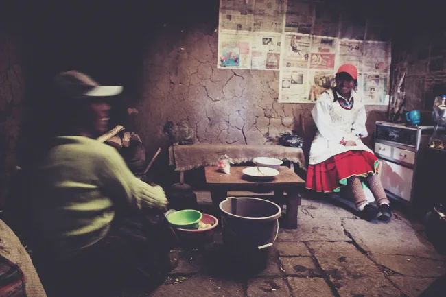 People preparing food in a dim, rustic kitchen.