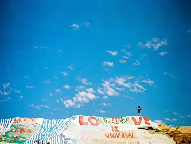Painted hillside at Salvation Mountain beneath a vivid blue sky.