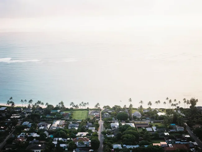 Oahu neighborhood and palm trees stretching toward a hazy ocean.