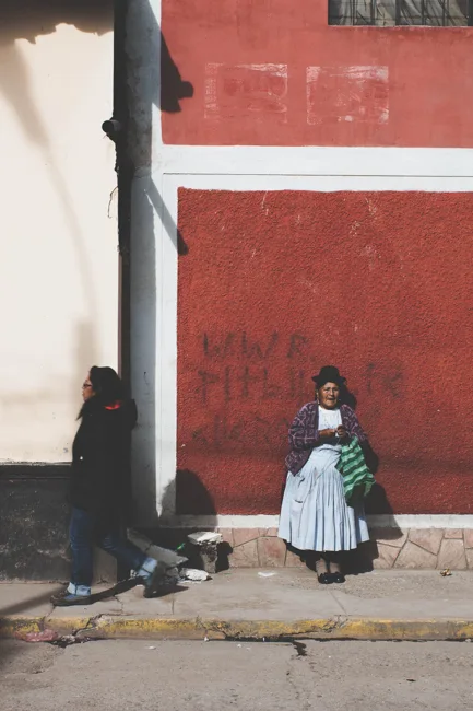 Person in traditional clothing standing beside a large red wall.