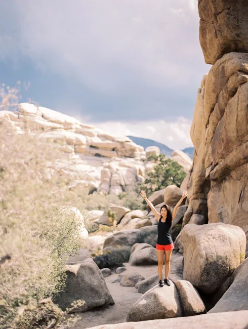 Hiker passing between tall rock formations in Joshua Tree.