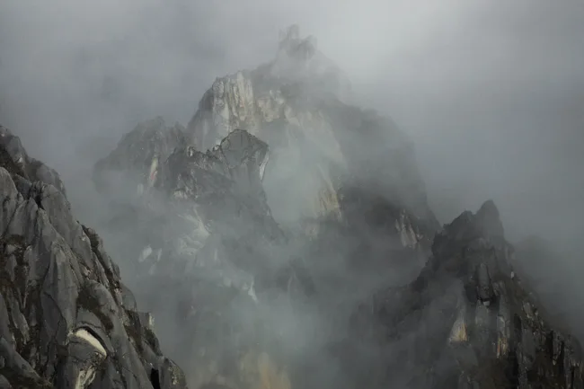 Jagged mountain peaks partly concealed by drifting cloud.