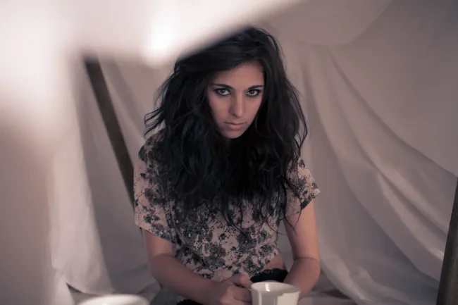 Model leaning forward in a patterned crop top against draped fabric.