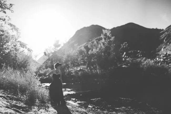 Black-and-white landscape with a figure among trees and mountains.