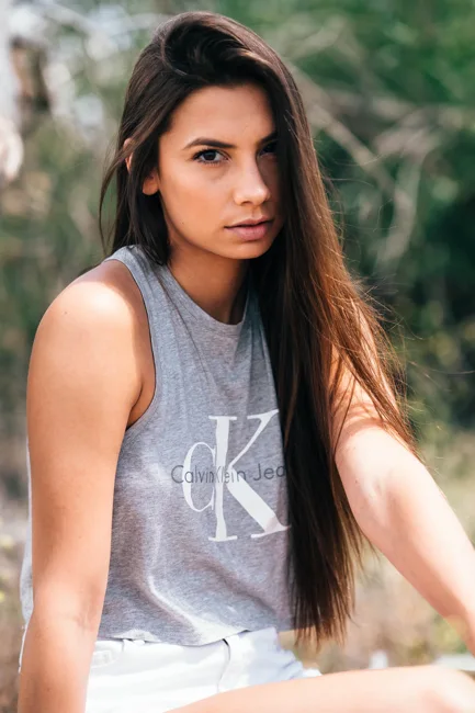 Outdoor portrait of a woman in a gray sleeveless top.