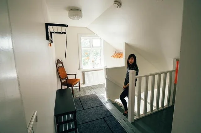 Woman standing by a stairway in a bright white interior.